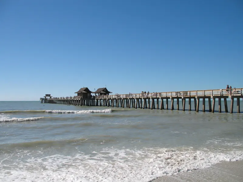 The Naples Pier seen from the surf along the Gulf beach in Naples, Florida